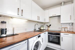 una cucina con armadietti bianchi e lavatrice di Reading Central Apartment a Reading