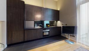 a kitchen with wooden cabinets and a tv in it at The Harrington - Gloucester Road - 1 Harrington Gardens in London