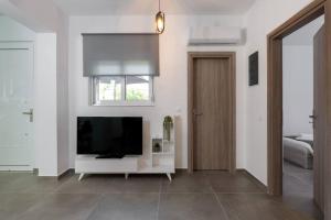 a living room with a television on a white wall at Michaela's Apartment in Koskinou