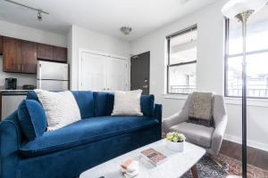 Una sala de estar con un sofá azul y una silla. en CozySuites Music Row Elegant 1BR w free parking 15, en Nashville