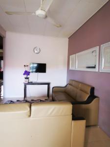 ein Wohnzimmer mit einem Sofa und einem TV in der Unterkunft Riqayraa Muslim Homestay in Seremban