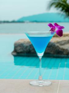 a blue drink in a martini glass with a purple flower at X-Sea Khanom Harbor Bay Resort in Ban Phang Phrao