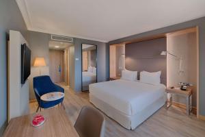 Habitación de hotel con cama blanca grande y escritorio. en NH Nice, en Niza