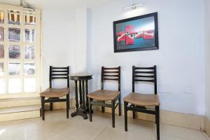 Hotel Homely Raj Near Kalighat Kali Temple في كولْكاتا: مجموعة كراسي وطاولة في الغرفة