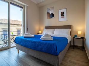 Un dormitorio con una cama con sábanas azules y una ventana. en My Home Catania Rooms, en Catania
