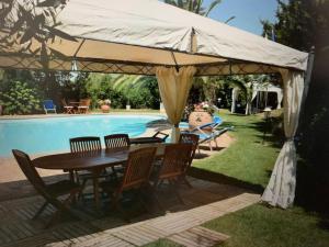 uma mesa e cadeiras debaixo de um guarda-sol ao lado de uma piscina em Villa at Tuscany border, swimming pool, golfcourse em Tarquinia