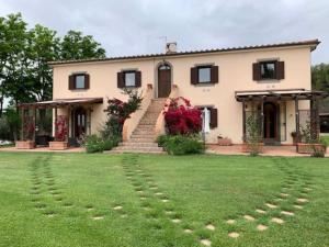 a house with a grassy yard in front of it at Villa at Tuscany border, swimming pool, golfcourse in Tarquinia