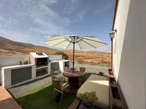 a patio with a table and an umbrella at Private villa with pool in the mountains in Pájara