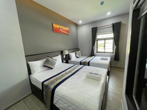 a bedroom with two beds and a window at Anna Hotel Binh Duong in Bến Cát