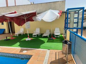 una piscina con sillas y sombrillas junto a un edificio en Acceso Sevilla Piscina Moderno Parking Gratis, en Bormujos