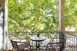 a table and chairs on a balcony with a tree at Aprtm Close To Arch Site & Museum Of Acropolis in Athens