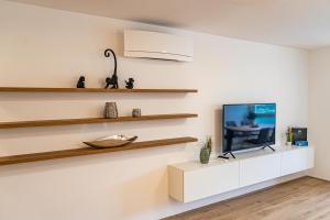 a living room with a tv on a white wall at Top 9 Alpe Maritima - Lakeview Apartment mit Bergkulisse in Annenheim