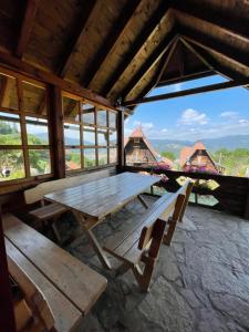 einen Holztisch und Bänke in einem Zimmer mit Fenstern in der Unterkunft Konak Mandica avlija in Zaovine