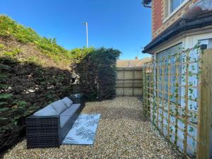 a couch sitting on a gravel path next to a fence at Luxury 2 bedroom maisonette with private garden, fibre WIFI, Sky channels in Camberley