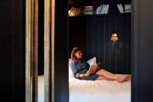 uma mulher sentada numa cama a ler um livro em La Grande École em Le Havre