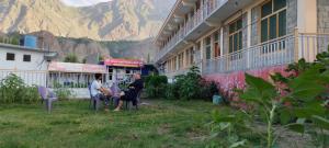 eine Gruppe von Personen, die vor einem Gebäude auf Stühlen sitzen in der Unterkunft Ghizer Inn Hotel And Resturant in Gākuch