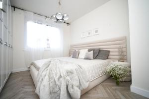 una camera bianca con un grande letto con una coperta di SZAFIROWE APARTAMENTY 3 kryty basen i sauna RESORT KLIFOWA a Rewal