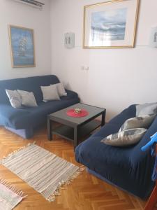 a living room with a blue couch and a table at Promajna apartman in Promajna