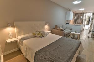 a bedroom with a large bed and a living room at Apartamentos Bela in Cangas de Morrazo
