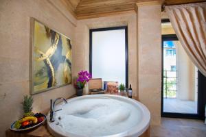 a large bath tub in a room with a large window at Cappadocia Pyramid Stone House in Uçhisar