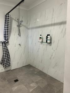 La salle de bains est pourvue d'une douche et de murs en marbre blanc. dans l'établissement Clermont Guest House - Pet friendly, à Clermont