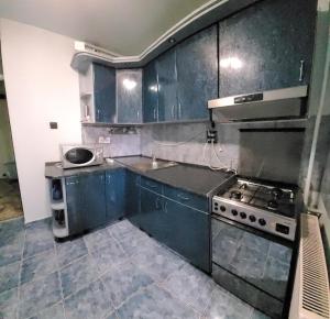 een keuken met blauwe kasten, een fornuis en een wastafel bij Ultracentral apartament -Mihaela in Arad