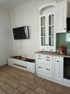 a kitchen with white cabinets and a flat screen tv at Villa Despina in Nea Iraklia