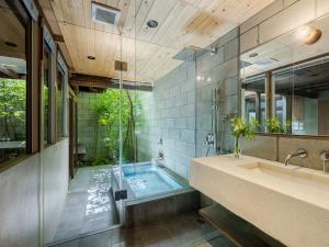 uma casa de banho com uma banheira, um lavatório e um espelho. em Yuzunoe Machiya House em Quioto