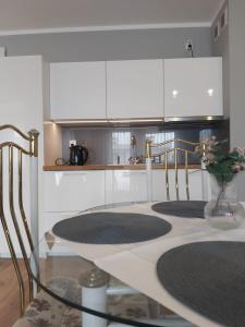 a kitchen with a glass table and white cabinets at Apartament Jarzębina in Kołobrzeg