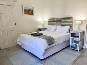 a bedroom with a large white bed and a door at Always Summer Guesthouse in Langebaan
