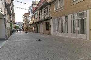 Une rue vide avec des bâtiments et des gens qui la descendent dans l'établissement Apartamentos Bela, à Cangas