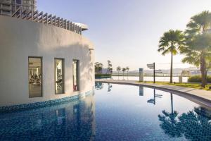 a swimming pool next to a building with palm trees at Teega Muji 4BR 12 pax w bathtub by Our Stay in Nusajaya