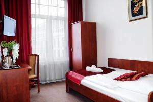 a bedroom with a bed and a desk and a window at Hotel Lothus in Wrocław