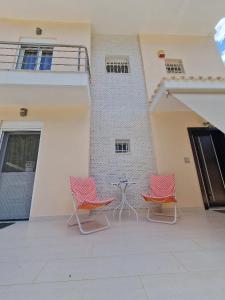 drie stoelen en een tafel voor een gebouw bij Sea Front Villa near Athens in Isthmia