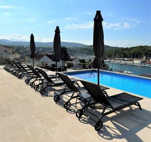 a row of lounge chairs and umbrellas next to a swimming pool at Villa Lovisa, private pool and amazing sea view in Milna