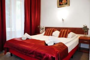 ヴロツワフにあるホテル ロータスの赤いカーテン付きのベッド2台が備わるホテルルームです。