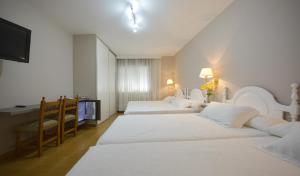 a hotel room with three beds and a desk at Hotel Jucamar in Cangas de Morrazo +37 photos