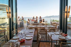 a restaurant with tables and chairs and a view of the ocean at Hôtel & Spa Belle Plage in Cannes