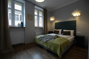 a bedroom with a bed with a green comforter and two windows at Starovka Apartament in Elblag