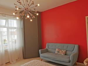 a living room with a couch and a red wall at Large Double Room with Private Toilet and Shower in Southend-on-Sea