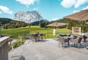 un patio con mesas, sillas y una montaña en Hotel Plan De Gralba - Feel the Dolomites, en Selva di Val Gardena