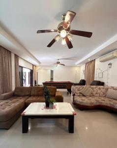 a living room with a couch and a ceiling fan at Blooming Hill Boutique Suites in Pattaya South