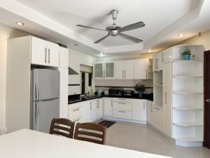 a kitchen with white cabinets and a ceiling fan at Blooming Hill Boutique Suites in Pattaya South