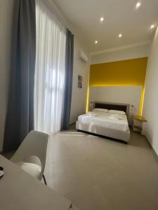 Un dormitorio con una cama blanca y una pared amarilla. en Dimora Chiaia 209, en Nápoles