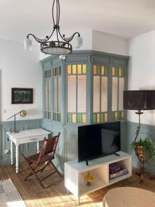 Elle comprend un salon avec une télévision et un bureau. dans l'établissement CHACHACHA appartement de charme calme balcon, à Mulhouse