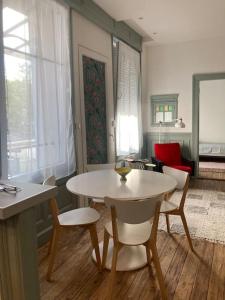a living room with a white table and chairs at CHACHACHA appartement de charme, calme,balcon 5pers 4étoiles, patio in Mulhouse +5 photos