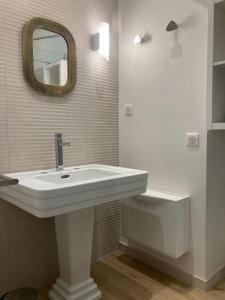een badkamer met een witte wastafel en een spiegel bij CHACHACHA appartement de charme calme balcon in Mulhouse
