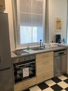 uma cozinha com um lavatório, um fogão e uma janela em CHACHACHA appartement de charme calme balcon em Mulhouse