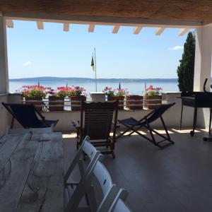 un patio con sillas y una mesa con vistas al océano en Verde Blu Lakefront Boutique Holiday Apartments Trevignano Romano en Trevignano Romano