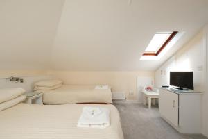 a white room with two beds and a television at Four Seasons B&B in Galway